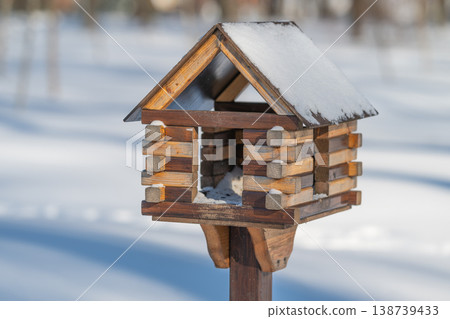 Snowcovered wooden birdhouse perched on post soft sunlight, birch forest background, crisp shadows, empty feeder, calm minimalist mood, shelter awaiting small birds 138739433