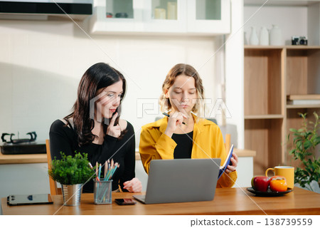 Two women working from home using laptop and phone. Teamwork, collaboration, freelance lifestyle, online business, remote work Two women working from home using laptop and phone. Teamwork, collaboration, freelance lifestyle, online business, remote work 138739559