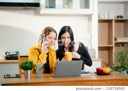 Two women working from home using laptop and phone. Teamwork, collaboration, freelance lifestyle, online business, remote work Two women working from home using laptop and phone. Teamwork, collaboration, freelance lifestyle, online business, remote work 138739563