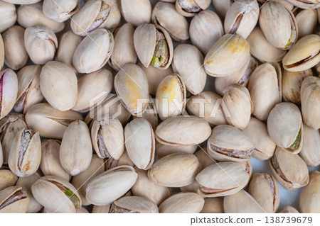Wide pistachio heap suggesting storage and commercial supply, dense mass of shelled nuts ready for packing or shipment, neutral tones for industrial food commerce contexts 138739679
