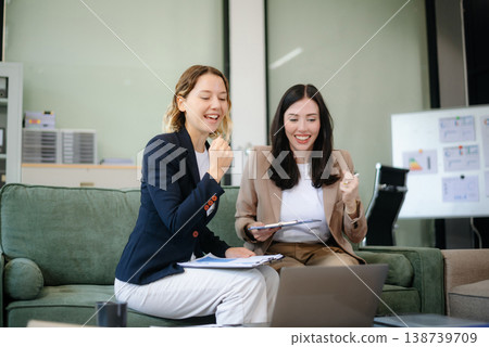 Two women collaborating on a project on sofa at home, brainstorming with a laptop and notebook Two women collaborating on a project on sofa at home, brainstorming with a laptop and notebook 138739709