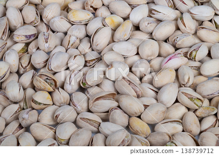 Tight macro pistachios texture, repeating pattern of closed and slightly open shells, pale tones with subtle purple streaks, crisp detail ideal for backgrounds and food design 138739712