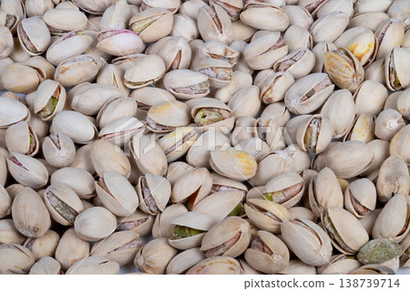 Pistachio shells scattered. Cracked shells display green kernels. Salted roasted pistachios with crispy texture. Premium gourmet pistachio snack on neutral surface Pistachio shells scattered. Cracked shells display green kernels. Salted roasted pistachios with crispy texture. Premium gourmet pistachio snack on neutral surface 138739714