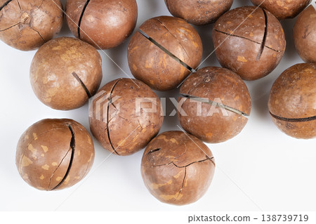 Still life of organic macadamia nuts on white background with shadows. Display of genuine organic macadamia nuts featuring subtle shadows and warm earthy color scheme Still life of organic macadamia nuts on white background with shadows. Display of genuine organic macadamia nuts featuring subtle shadows and warm earthy color scheme 138739719