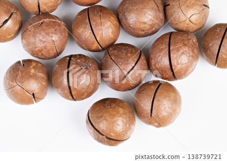 Nuts on white surface. Separate macadamia nuts displayed against plain white backdrop. Singly arranged macadamia nuts showcasing different shell shades on blank background 138739721