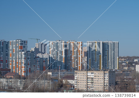 Colorful cityscape with new buildings. Vivid urban outline with bright facades and cranes. Dynamic city skyline featuring colorful structures and reflective glass surfaces Colorful cityscape with new buildings. Vivid urban outline with bright facades and cranes. Dynamic city skyline featuring colorful structures and reflective glass surfaces 138739814