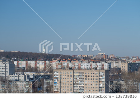 Modern cityscape with prominent church tower and layered roof designs. Urban environment showcasing religious building with tall spire and surrounding rooftop layers 138739816