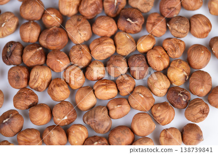 Closeup hazelnut kernels on white backdrop, warm rustic tones, scattered arrangement, textured skins and subtle shadows, cozy snack mood for packaging and food blogs 138739841