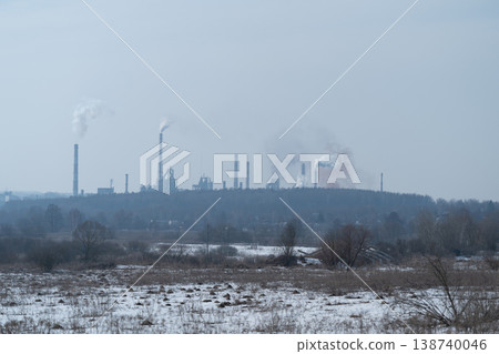 Distant metallurgical plant across icy plain, pale blue tones and low contrast, scattered smoke plumes, tree line between field and complex, serene yet industrial scene Distant metallurgical plant across icy plain, pale blue tones and low contrast, scattered smoke plumes, tree line between field and complex, serene yet industrial scene 138740046