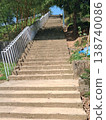 Concrete Outdoor Stairs With White Railing Rising Uphill Through Green Trees and Sunlit Pathway 138740086