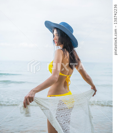 Woman stands barefoot near ocean waves Woman stands barefoot near ocean waves 138742236