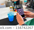 Close-up of a person scanning a QR code on a smartphone to pay for a drink at a cafe. Cashless transaction, mobile banking, and contactless payment technology in modern everyday lifestyle 138742267