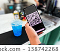 Close-up of a person scanning a QR code on a smartphone to pay for a drink at a cafe. Cashless transaction, mobile banking, and contactless payment technology in modern everyday lifestyle 138742268