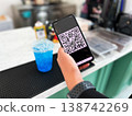 Close-up of a person scanning a QR code on a smartphone to pay for a drink at a cafe. Cashless transaction, mobile banking, and contactless payment technology in modern everyday lifestyle 138742269