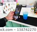 Close-up of a person scanning a QR code on a smartphone to pay for a drink at a cafe. Cashless transaction, mobile banking, and contactless payment technology in modern everyday lifestyle 138742270