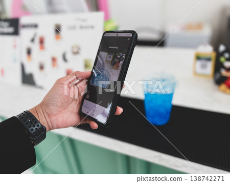Close-up of a person scanning a QR code on a smartphone to pay for a drink at a cafe. Cashless transaction, mobile banking, and contactless payment technology in modern everyday lifestyle Close-up of a person scanning a QR code on a smartphone to pay for a drink at a cafe. Cashless transaction, mobile banking, and contactless payment technology in modern everyday lifestyle 138742271