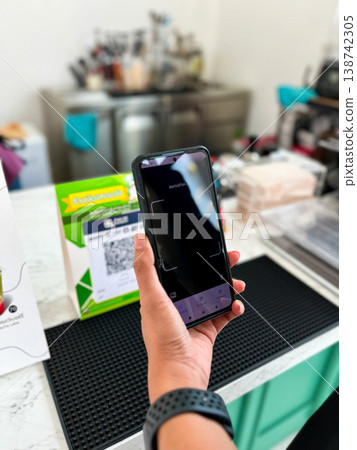 a person using a smartphone to scan a QR code for digital payment at a cafe counter. Modern cashless transaction, mobile banking, and contactless technology in everyday lifestyle a person using a smartphone to scan a QR code for digital payment at a cafe counter. Modern cashless transaction, mobile banking, and contactless technology in everyday lifestyle 138742305