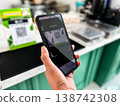 a person using a smartphone to scan a QR code for digital payment at a cafe counter. Modern cashless transaction, mobile banking, and contactless technology in everyday lifestyle 138742308