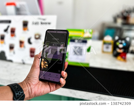 a person using a smartphone to scan a QR code for digital payment at a cafe counter. Modern cashless transaction, mobile banking, and contactless technology in everyday lifestyle a person using a smartphone to scan a QR code for digital payment at a cafe counter. Modern cashless transaction, mobile banking, and contactless technology in everyday lifestyle 138742309