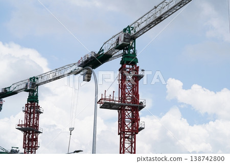 Construction Cranes Against Cloudy Sky Construction Cranes Against Cloudy Sky 138742800