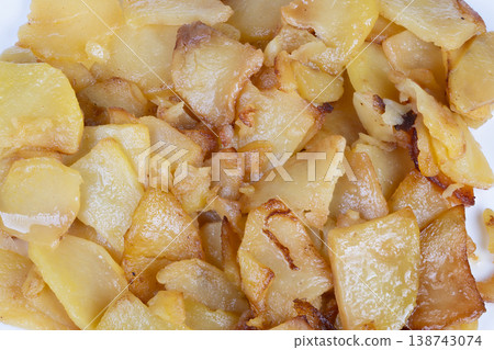 Closeup of crispy fried potatoes. Texture and surface of golden fried potatoes. Closeup photograph capturing crunchiness and rustic appeal of seasoned fried potato slices Closeup of crispy fried potatoes. Texture and surface of golden fried potatoes. Closeup photograph capturing crunchiness and rustic appeal of seasoned fried potato slices 138743074