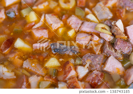 Closeup of grandma homemade soup with cured meat cubes and pickle slices, golden broth with rustic texture and nostalgic homecooked atmosphere, timeless comfort classic 138743185