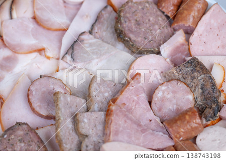 Closeup of regional meat assortment with hearty textures and seasoning. Focused view of regional meat platter featuring smoked sausages and cured ham slices with savory taste Closeup of regional meat assortment with hearty textures and seasoning. Focused view of regional meat platter featuring smoked sausages and cured ham slices with savory taste 138743198