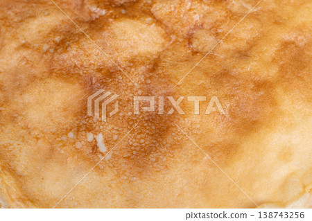 Soft lighting highlights pancake layers. Minimalist brunch with gentle illumination and subtle details. Serene culinary arrangement featuring thin pancakes on white dish 138743256