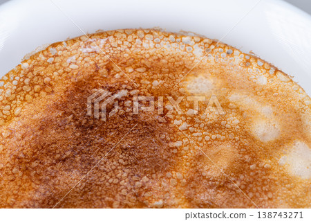 Golden pancake closeup. Detailed surface of pancake shown. Zoomedin view highlighting pancake surface details. Closeup photograph emphasizing texture of golden pancake surface 138743271