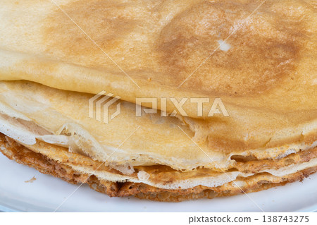 Soft folded pancake with appealing browning displayed. Delicately folded pancake slice exhibiting rich textures and inviting surface color for appealing culinary images Soft folded pancake with appealing browning displayed. Delicately folded pancake slice exhibiting rich textures and inviting surface color for appealing culinary images 138743275