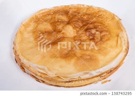 Stack golden pancakes on white plate, thin layers with even browning, simple studio lighting emphasizing texture and circular shape, neutral background for versatile food styling 138743295