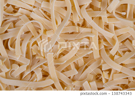 Egg noodles display. Heaping mound of yellow noodles. Close view of pale yellow noodle pile. Detailed shot of heap of pale yellow egg noodles with flour accents 138743343