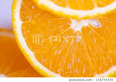 Detailed macro view of juicy orange segments illuminated brightly. Highresolution image showcasing fresh orange pieces with textured pulp and shimmering droplets 138743345