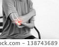 Monochrome photo of woman suffering from severe elbow pain, holding her arm with a red glowing anatomical bone graphic overlay showing joint inflammation, arthritis, or injury in medical concept. 138743689