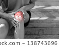 Monochrome photo of person holding painful knee with red glowing anatomical bone graphic overlay showing joint inflammation, sports injury, or severe arthritis in medical and healthcare concept. 138743696