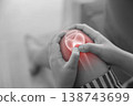 Monochrome photo of hands holding a sore knee with red glowing anatomical bone graphic overlay showing joint inflammation, pain, or arthritis in healthcare concept and medical diagnosis. 138743699