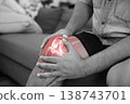 Monochrome photo a man with knee joint pain, holding his sore leg with a glowing red anatomical skeleton diagram overlay, illustrating osteoarthritis, injury, or inflammation. Healthcare medical. 138743701