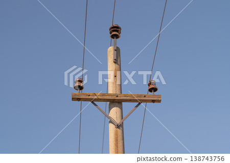 Photograph emphasizing textures of aged utility pole structures. Vertical composition showcasing textures and simplicity of weathered electric poles with insulators 138743756