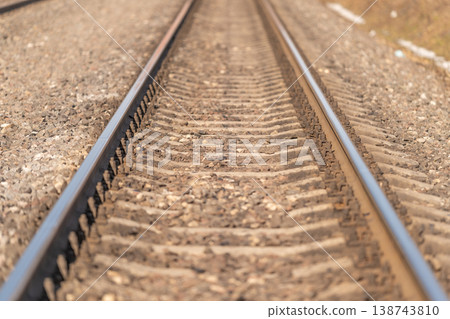 Track this visual. Journey along rhythmic railway lines. Receding railway ties and structured tracks. Serene travel scene with repetitive railway track patterns and ballast Track this visual. Journey along rhythmic railway lines. Receding railway ties and structured tracks. Serene travel scene with repetitive railway track patterns and ballast 138743810