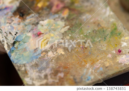 Art color preparation. Macro view of palette with dried paint layers and tools. Detailed perspective of artist organizing pigment swathes for portrait creation process 138743831