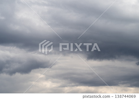 Heavy gray clouds gather above horizon. Overcast sky with threatening storm clouds looming overhead. Foreboding storm clouds cast dark and dramatic atmosphere across sky Heavy gray clouds gather above horizon. Overcast sky with threatening storm clouds looming overhead. Foreboding storm clouds cast dark and dramatic atmosphere across sky 138744069