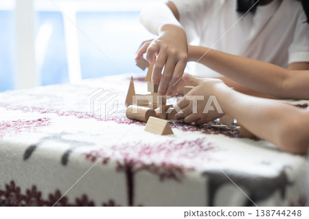 Children play with wooden blocks at a table in a calm home environment supporting creativity, learning, and early childhood development. Children play with wooden blocks at a table in a calm home environment supporting creativity, learning, and early childhood development. 138744248