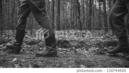 Low angle view of two Wehrmacht soldiers walking in boots through forest Low angle view of two Wehrmacht soldiers walking in boots through forest 138744608