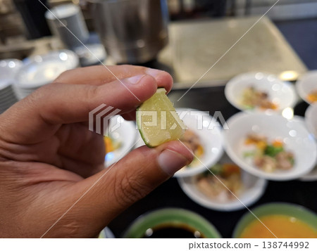 Hand holding a fresh lime wedge for an appetizing meal Hand holding a fresh lime wedge for an appetizing meal 138744992