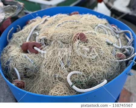 Fishing net tangled in blue container on dock, capturing maritime life and fishing industry Fishing net tangled in blue container on dock, capturing maritime life and fishing industry 138745567