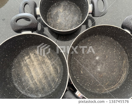 Overhead view of three black cooking pots with visible wear on non-stick surfaces Overhead view of three black cooking pots with visible wear on non-stick surfaces 138745576
