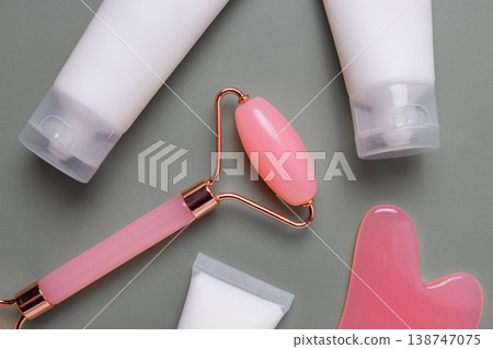 Facial roller, gua sha and cosmetic skincare tubes close up on neutral background, beauty routine concept Facial roller, gua sha and cosmetic skincare tubes close up on neutral background, beauty routine concept 138747075
