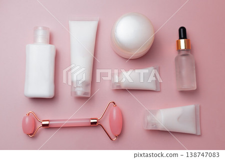 Skincare cosmetic products flat lay with facial roller, cream jar, serum dropper and lotion tubes on pink background, beauty routine concept 138747083