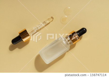 Cosmetic serum dropper bottle with skincare liquid drops on warm pastel background, beauty treatment concept 138747114
