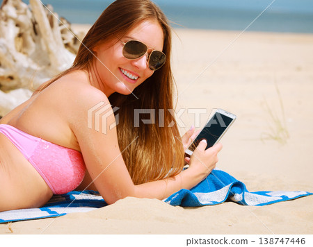 Woman on beach texting on smartphone. Woman on beach texting on smartphone. 138747446